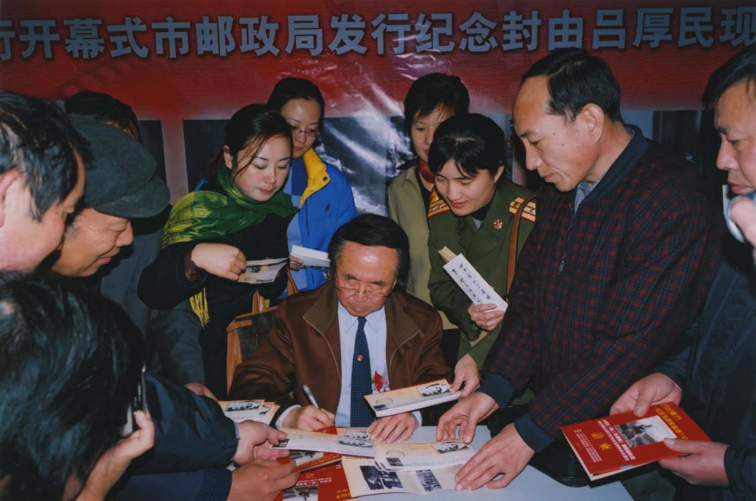 吕厚民为观众在纪念封上签名留念.jpg