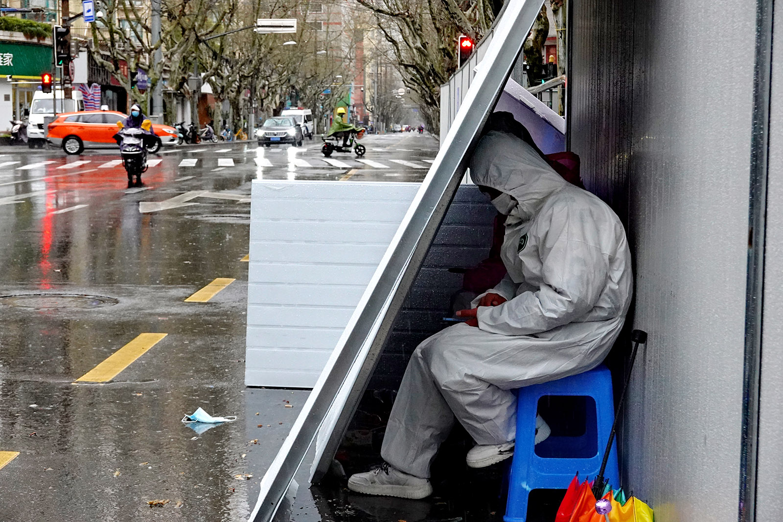 2022年3月21日，一名穿着防护服的防疫工作人员在挡板后避雨。王定森 图