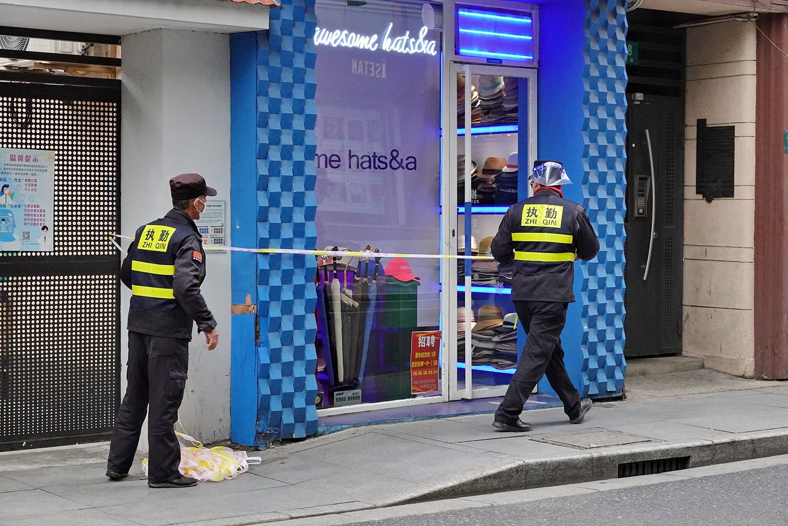 2022年3月19日，南汇路上，两位执勤人员在一家店前拉上警戒线。王定森 图