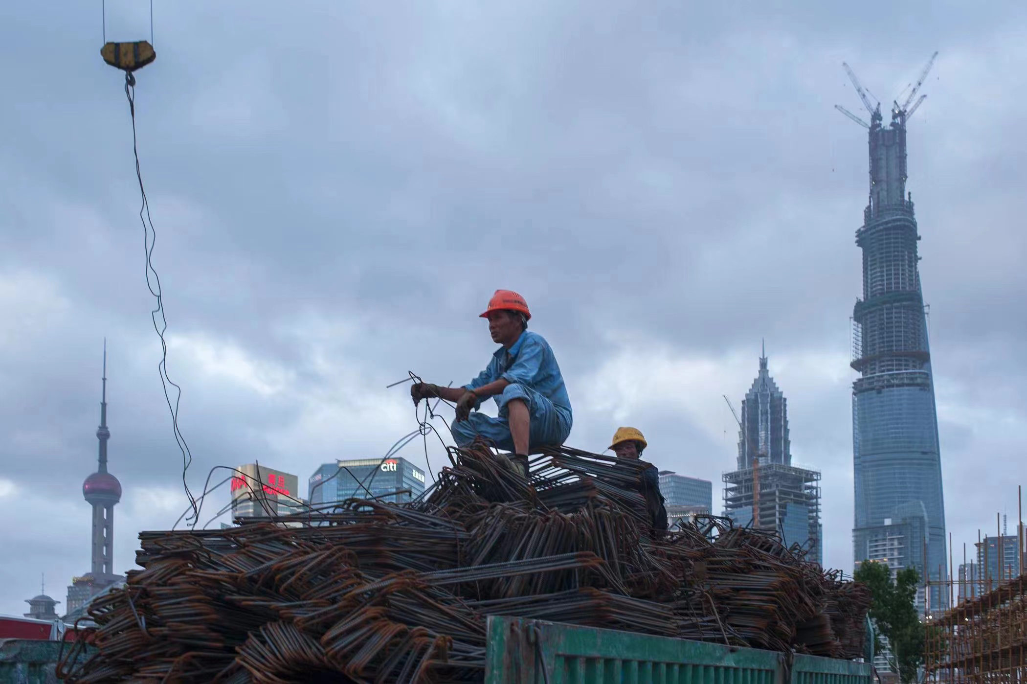 2013年7月13日，中国上海，豫园附近的一个建筑工地上，一名建筑工人坐在一辆满载钢材的卡车上。