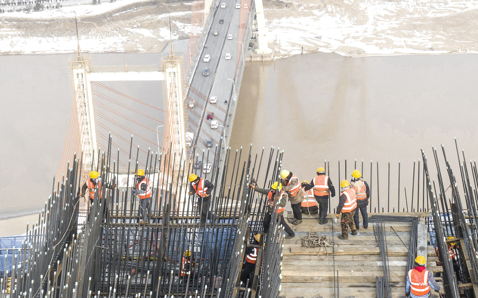 《建设中的黄河大桥》组照  2023年1月16日，大雪过后，工人们不顾寒冷、风大立即复工，确保大桥工程进度。.jpg